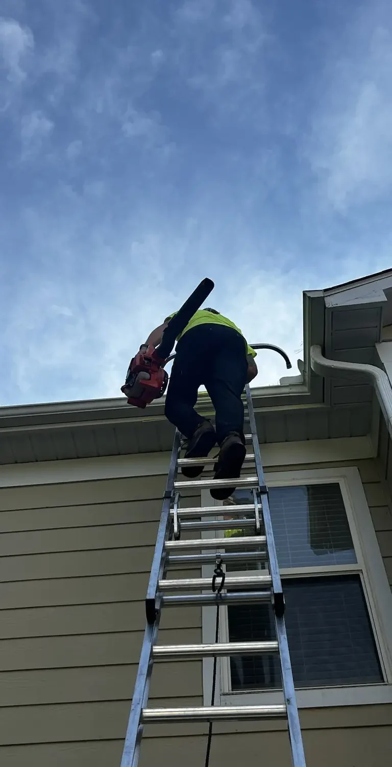 Technician cleaning commercial gutters during routine maintenance service