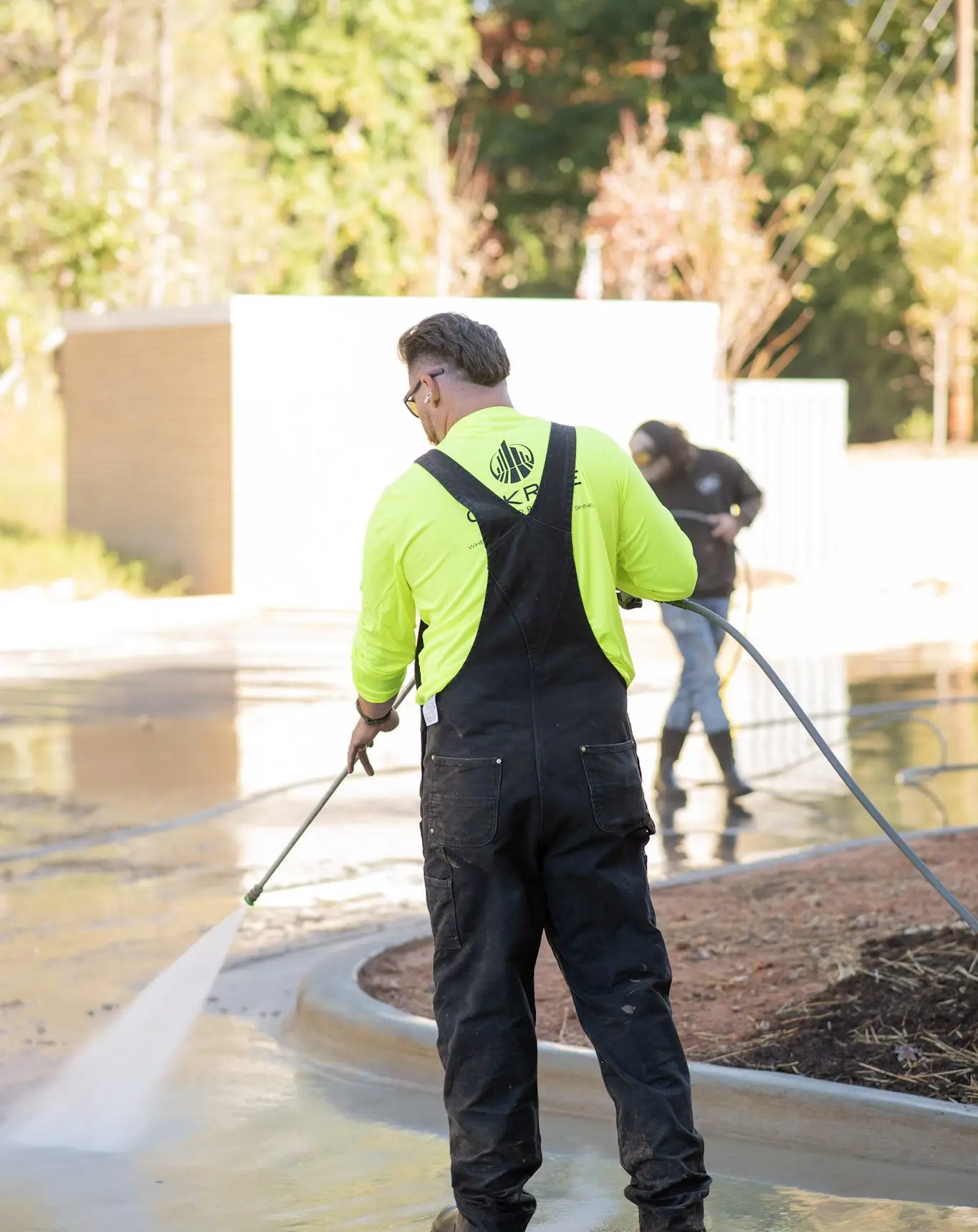 Technician cleaning parking deck concrete with high-flow pressure washer
